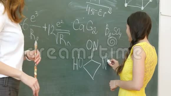在一节化学课上年轻的女大学生在黑板上写字视频的预览图