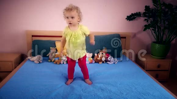 顽皮的蹒跚学步的女孩在卧室里跳跃和跌倒视频的预览图