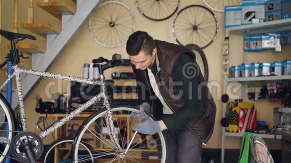 英俊的男机修工正在用专业工具修理自行车车轮同时独自在小作坊工作视频的预览图