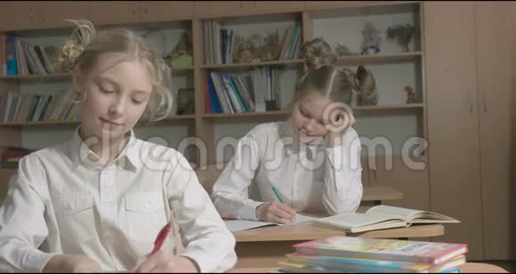 孩子们或两个快乐的女孩在学校教室里学习和做作业视频的预览图