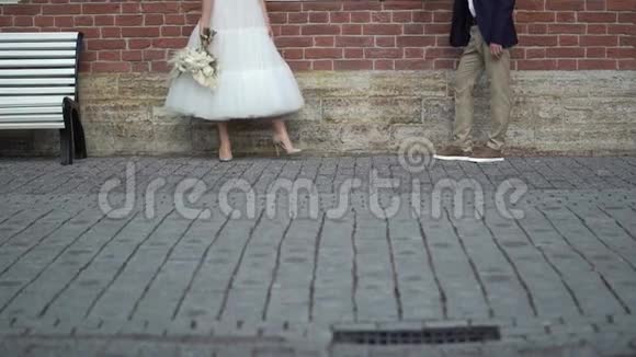 新娘和新郎在城市里散步年轻可爱的新婚夫妇新娘花束视频的预览图