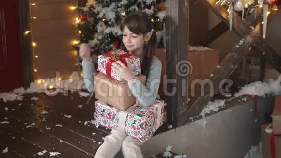 圣诞节或新年小女孩手里拿着一个盒子手里拿着礼物狡猾地微笑着孩子收到了许多礼物视频的预览图