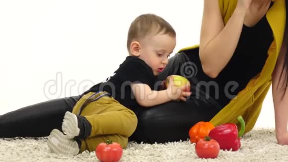 小孩子吃苹果挨着妈妈白色背景视频的预览图