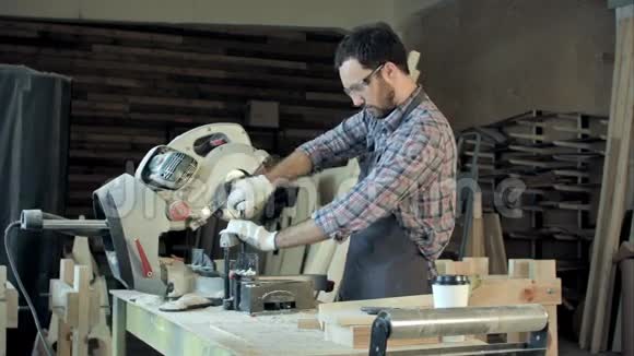 有胡子的年轻木匠用电锯砍木板视频的预览图