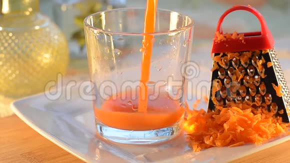 胡萝卜汁倒入一个玻璃烧杯中杯子站在桌子和盘子上有选择的焦点视频的预览图