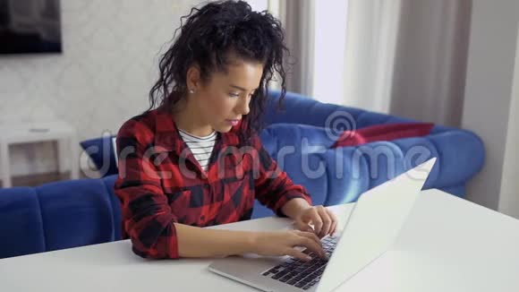 年轻漂亮的黑发女人在家里打手提电脑视频的预览图