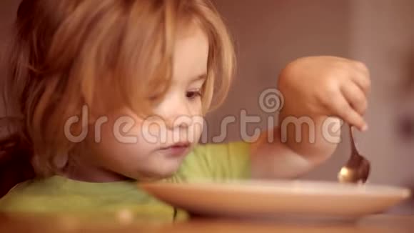 快乐的孩子快乐的婴儿用勺子吃食物快乐的小男孩勺子吃自己小宝宝在吃东西视频的预览图