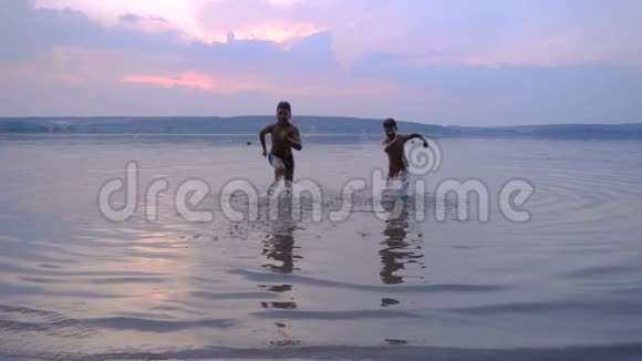 两个男孩在日落时从水中奔跑视频的预览图