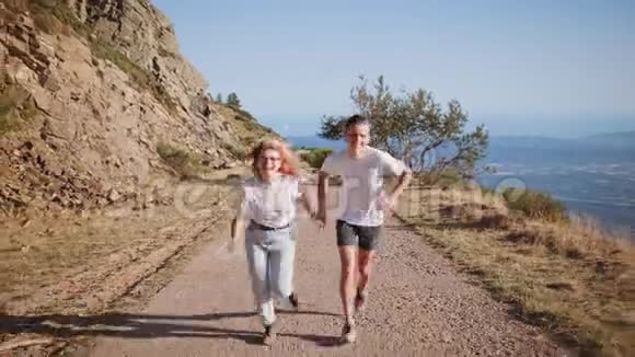 年轻的时髦情侣在日落的山路上徒步旅行视频的预览图