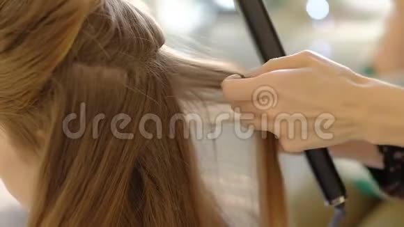 一个女理发师用一个烫发器给客户做一个巨大的发型卷曲的头发专业理发师视频的预览图