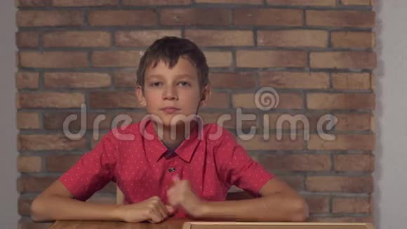 坐在书桌前的孩子拿着一张挂图背景红砖墙上有刻字的休息日视频的预览图