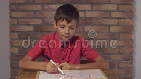 坐在办公桌前的孩子拿着一张挂图背景红砖墙上刻着百万字视频的预览图