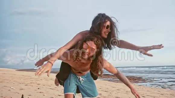 迷人的年轻和精力充沛的夫妇在海滩上玩得很开心女人骑着一个男人笑海洋夏季视频的预览图