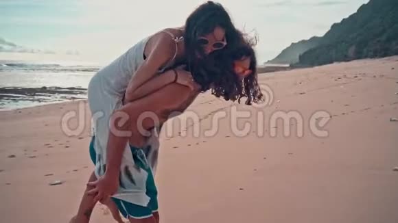 迷人的年轻和精力充沛的夫妇在海滩上玩得很开心女人骑着一个男人笑海洋夏季视频的预览图