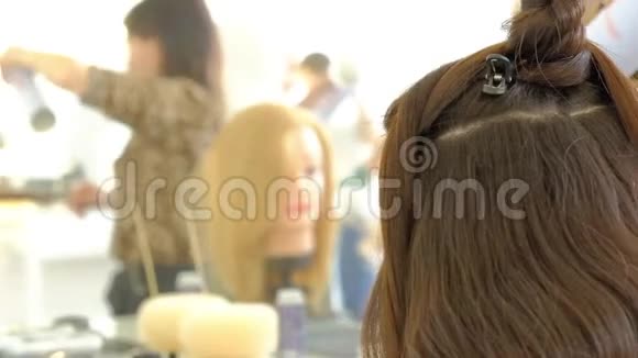 一个女理发师用一个烫发器给客户做一个巨大的发型卷曲的头发专业理发师视频的预览图