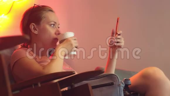 这个女孩正在复古咖啡馆里喝着一杯饼干的咖啡然后浏览她的手机4K慢动作视频的预览图