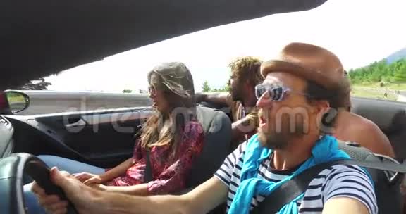 戴帽子的留胡子的时髦男人和朋友一起坐敞篷车听音乐视频的预览图