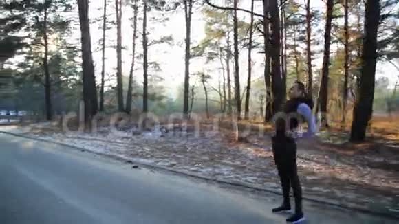 运动的中年妇女在一条土路上的绿色森林里伸展然后跑了视频的预览图