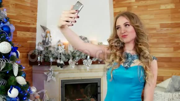 女孩自拍一部手机的圣诞照片一个圣诞树上的节日派对一个漂亮的女孩用手机视频的预览图
