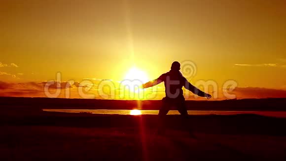 人走在夏日草甸夕阳西下山顶上年轻人的剪影视频的预览图