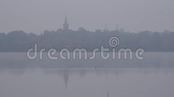 秋天的早晨湖岸的教堂塔在浓雾中放大4K视频的预览图