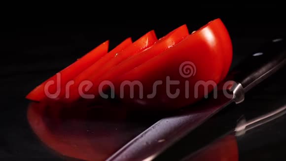 在黑色背景的黑色桌子上用一把旋转的刀切割成熟的番茄视频的预览图