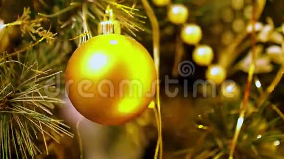 挂在人造杉木上的金色圣诞球的特写闪烁着黄灯的圣诞树花环视频的预览图