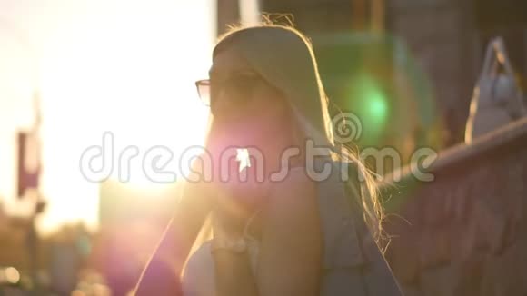 迷人的女孩走在城市的街道上转向相机微笑美丽的金发碧眼视频的预览图