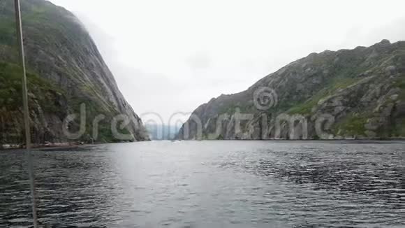 在多云天气的平静水域中从游艇板上看到Trollfjord视频的预览图