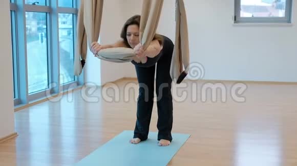 在空中练习瑜伽的成年女子在吊床上做伸展运动视频的预览图