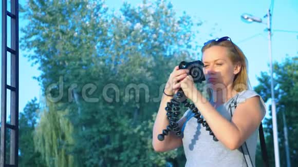 一个职业摄影师在游乐园拍照一个女人在开花间按下一个小玩意的按钮视频的预览图