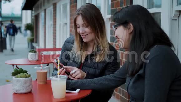 两个年轻的女人坐在街头咖啡馆里放松视频的预览图