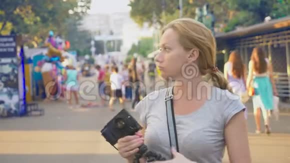 一个职业摄影师在游乐园拍照一个女人在开花间按下一个小玩意的按钮视频的预览图