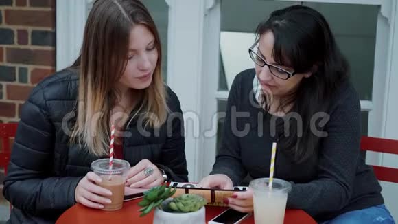 两个年轻的女人坐在街头咖啡馆里放松视频的预览图