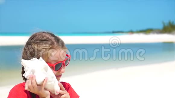 小可爱女孩在海滩上听一个大贝壳的肖像流动人口视频的预览图