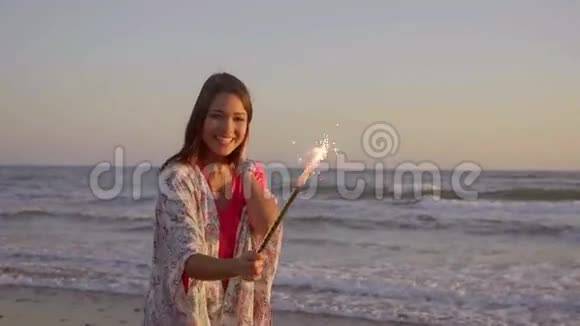 海滩上有喷泉蜡烛的布鲁内特女士视频的预览图