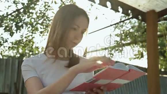 描绘年轻漂亮的女人在读一本书坐在长凳上的女人视频的预览图