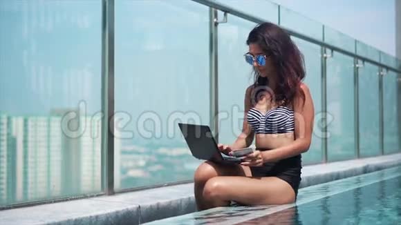 在阳光明媚的一天女人在游泳池里在线付款视频的预览图