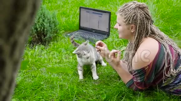 她在户外喂猫在笔记本电脑后面工作视频的预览图