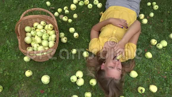 年轻女子躺在果园的草地上吃多汁的苹果4K视频的预览图