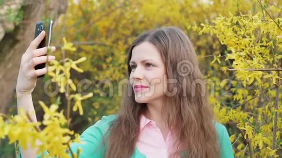 美丽的女孩在黄花春树中自拍视频的预览图