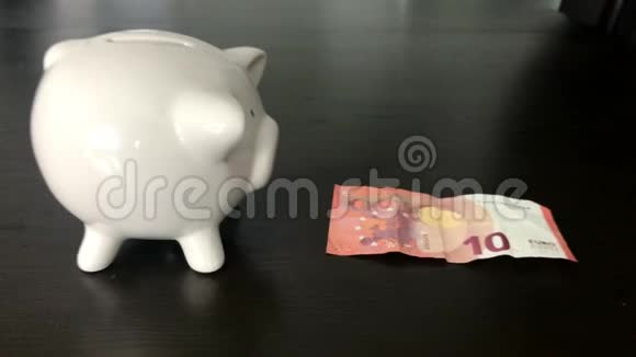 一个女人把10欧元的钞票放进储蓄罐视频的预览图