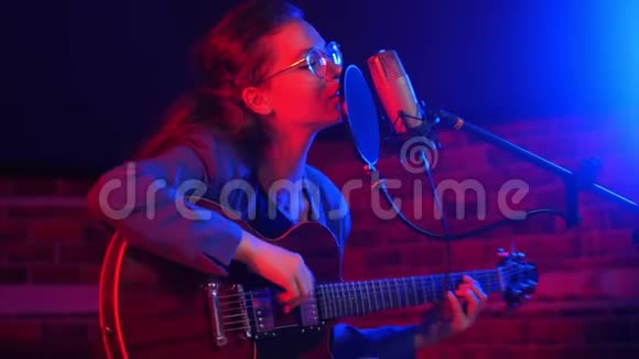 一位戴眼镜的年轻女子在霓虹灯中弹吉他和唱歌视频的预览图