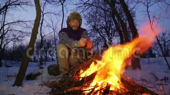 有胡子的人在冬天的炉火旁暖手游客晚上篝火视频的预览图