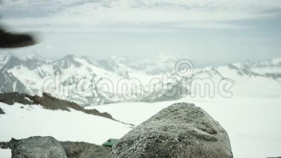 雪山景色下徒步旅行者穿着皮鞋踩在岩石上视频的预览图