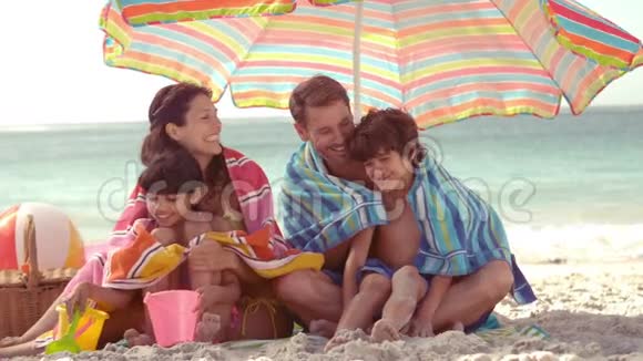 幸福的家庭坐在阳伞下视频的预览图