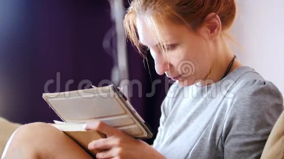 一个漂亮女人坐在沙发上拿着小玩意和笔记本工作的肖像视频的预览图