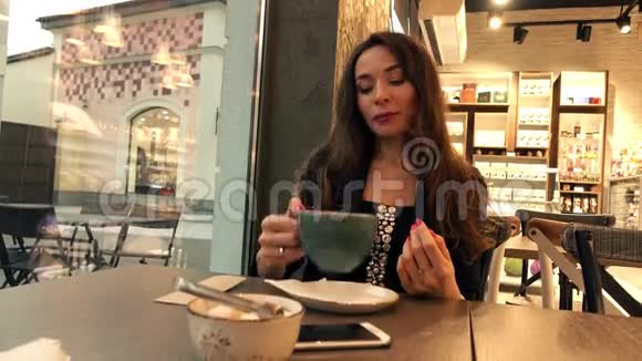 美丽的白种人黑发女孩在咖啡馆喝热巧克力4K视频视频的预览图