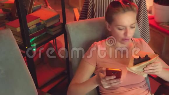 这个女孩正在复古咖啡馆里喝着一杯饼干的咖啡然后浏览她的手机4K慢动作视频的预览图