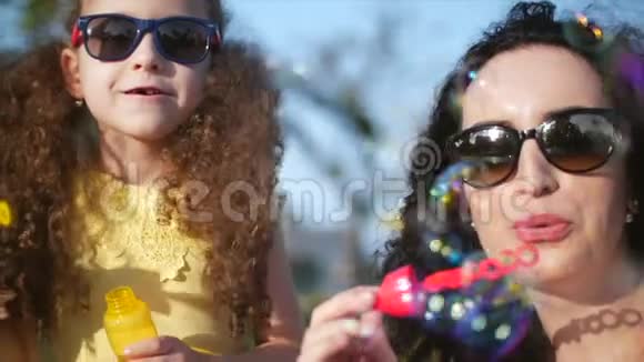幸福微笑的家人妈妈和女儿正在玩耍在夏天的户外吹肥皂泡库存录像视频的预览图